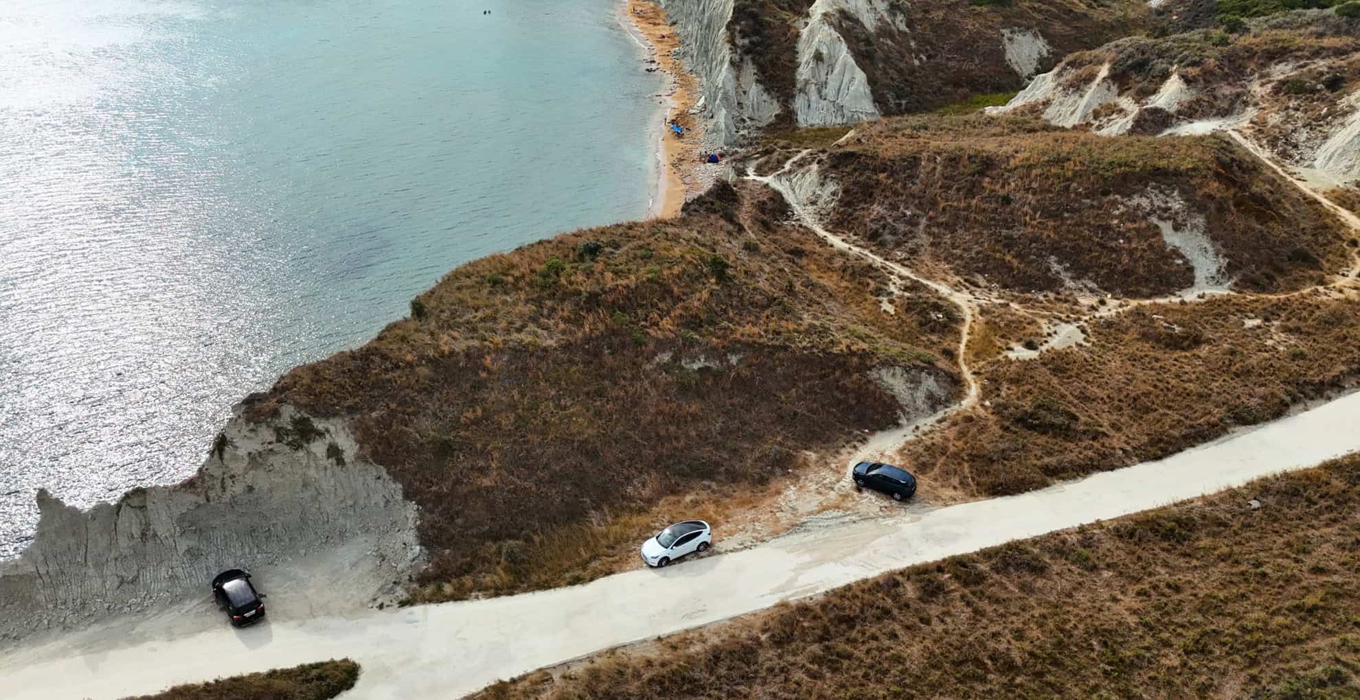 The parking area located near the secluded Koutala Beach, with a dirt path leading to the shore.